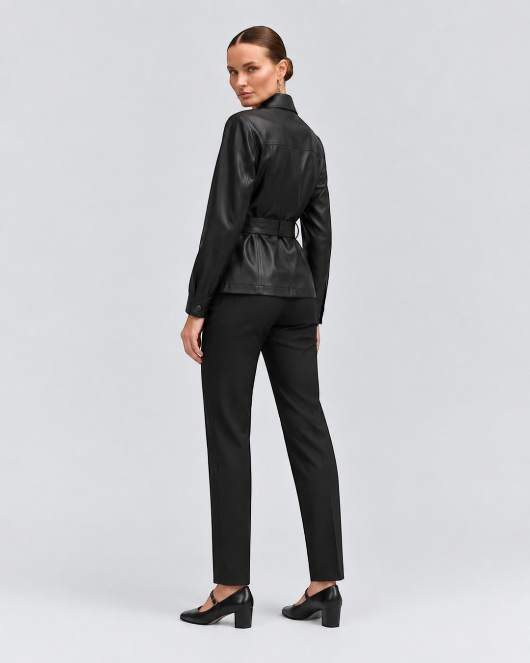 Luna Moda black PU leather jacket with adjustable belt worn by a model, back view showing tailored fit and pockets.
