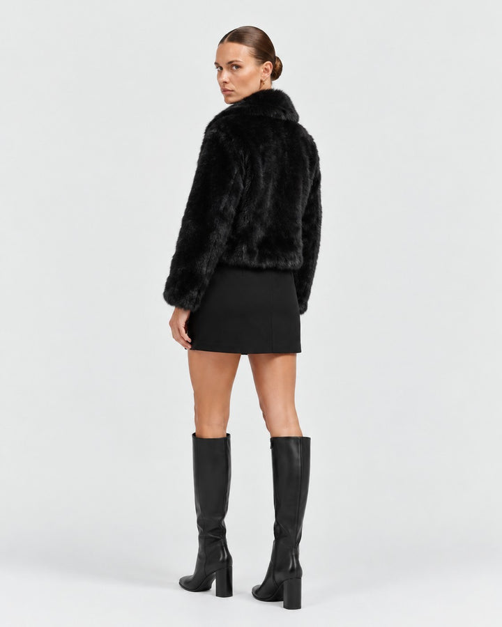 Luna Moda Debora black faux fur cropped jacket worn by a model with a black mini skirt and knee-high boots