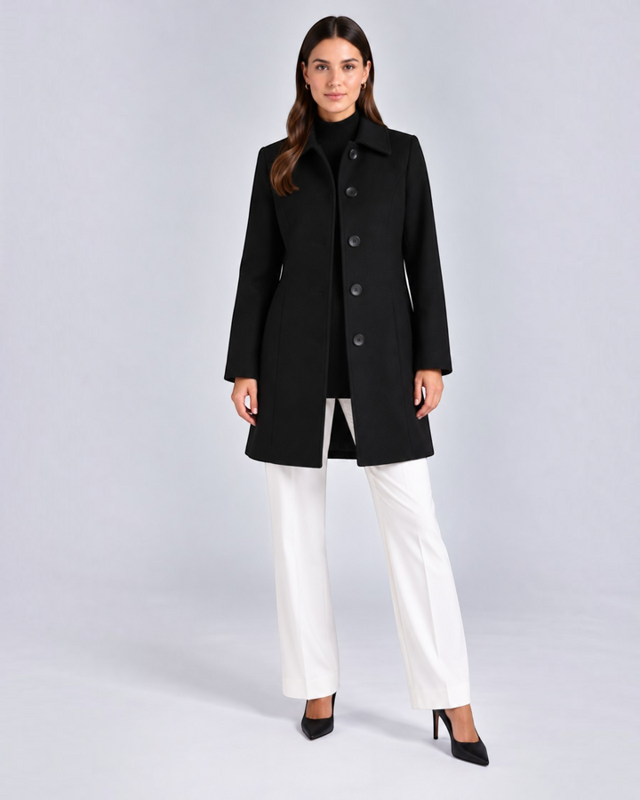 Luna Moda black fit and flare coat with a classic collar and button closure worn by a model with white trousers