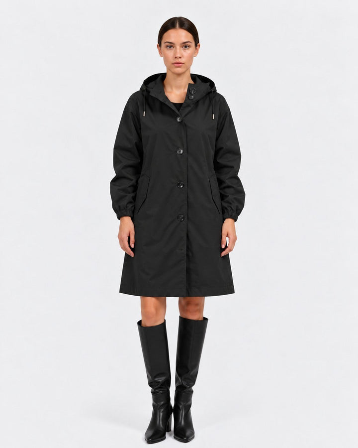 Luna Moda black oversized waterproof raincoat with hood and pockets worn by a model with black knee-high boots