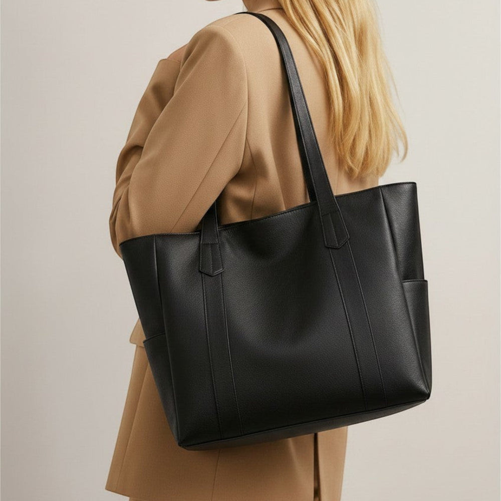 Luna Moda Mariana black minimalist shopper bag with double handles worn over the shoulder by a woman in a blazer