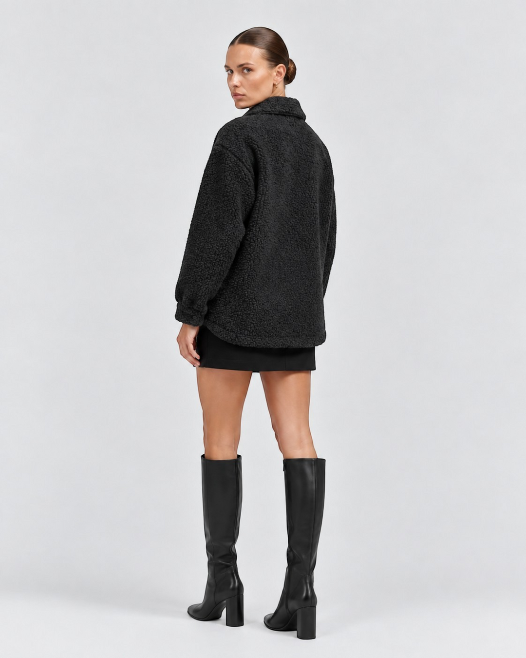 Luna Moda black textured short jacket with lapel collar worn by a model with a black skirt and knee-high boots