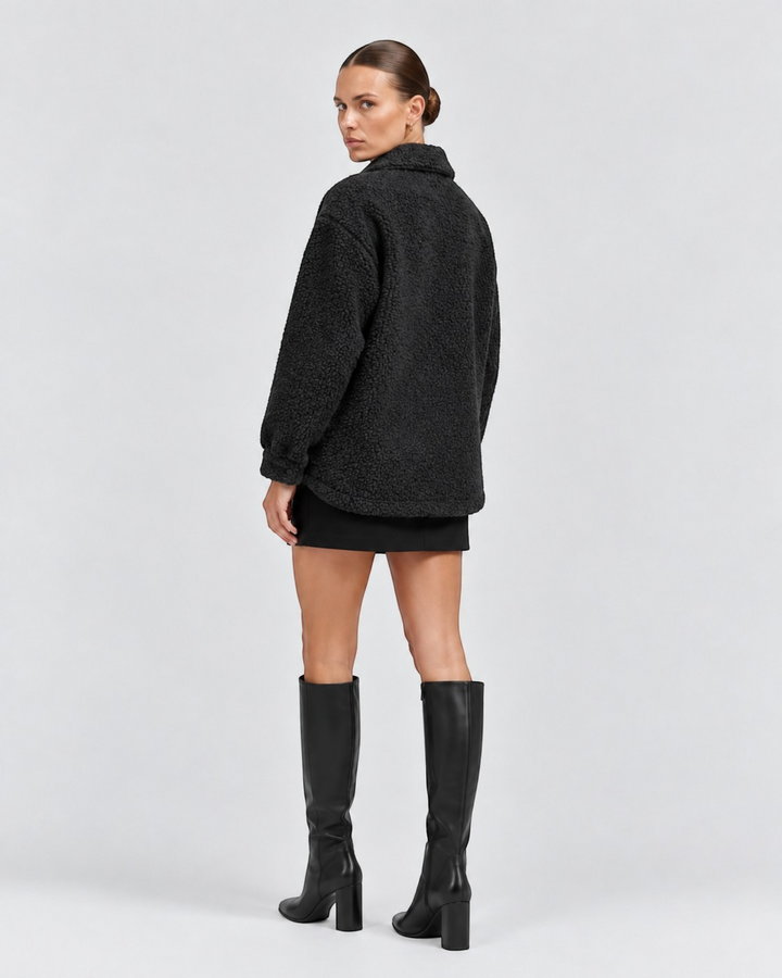 Luna Moda black textured short jacket with lapel collar worn by a model with a black skirt and knee-high boots