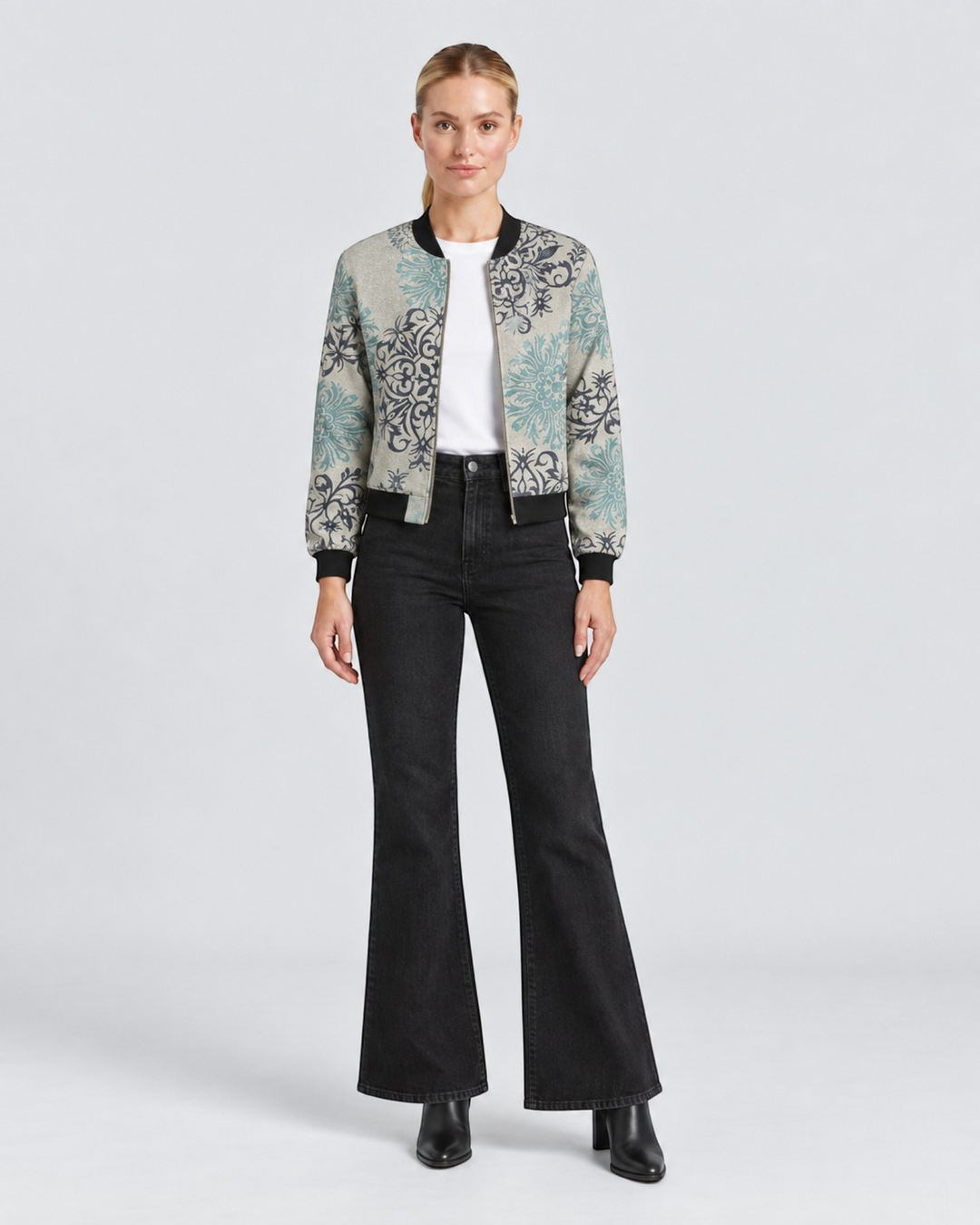 Luna Moda Sofia bomber jacket with botanical print in grey and teal, worn by a model with black flared jeans.