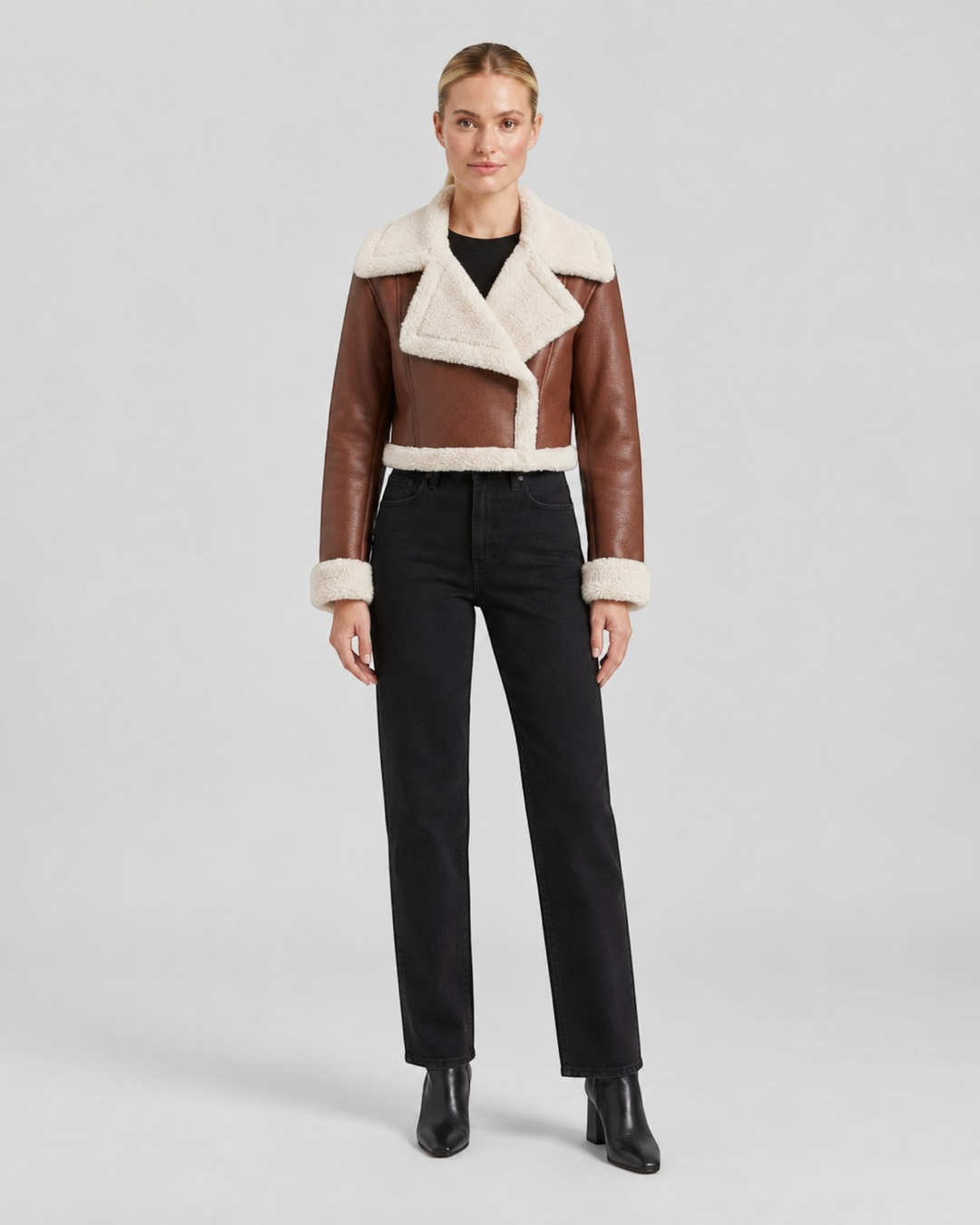 Luna Moda cropped brown faux leather jacket with cream fleece lining worn by a model with black jeans and boots.