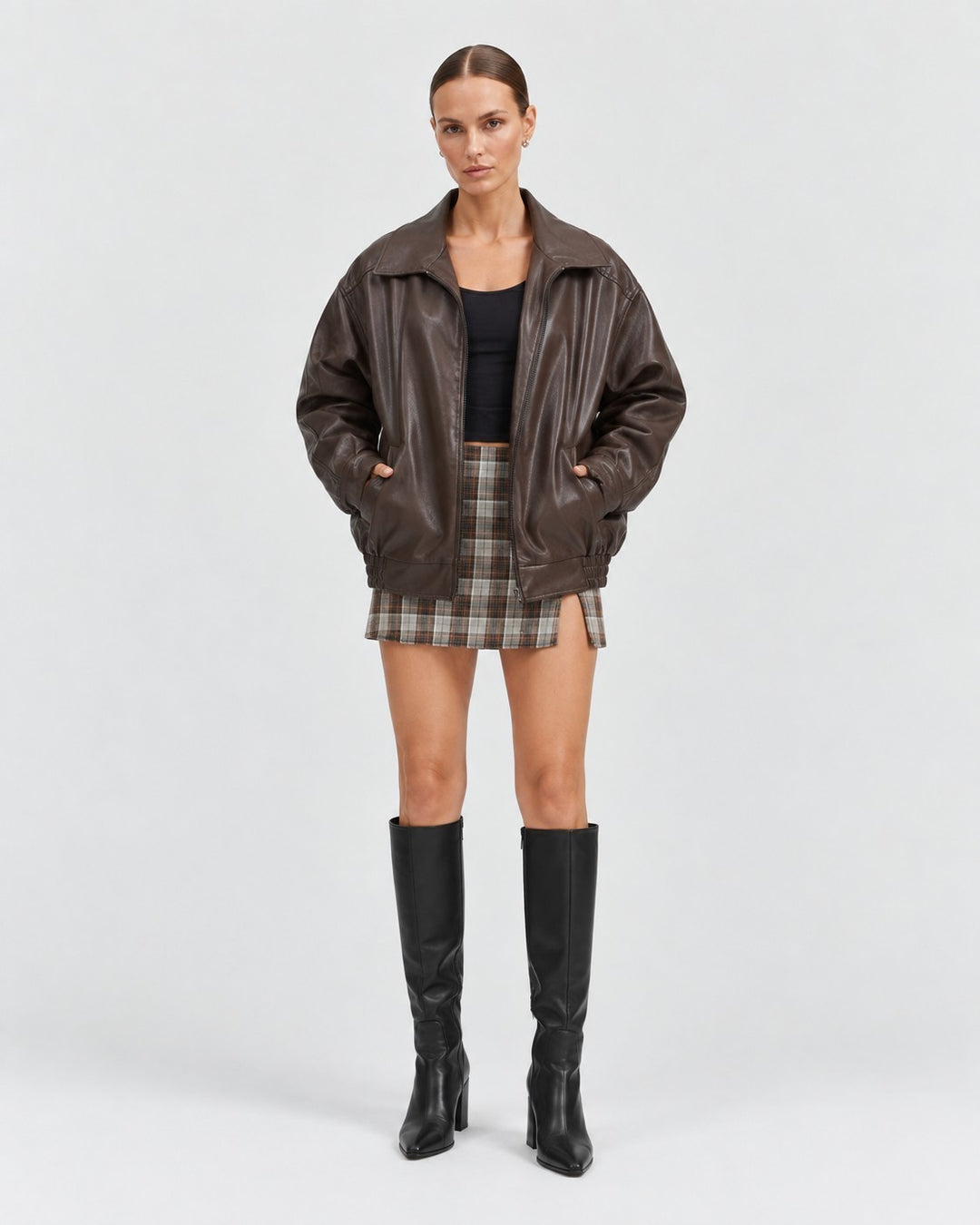 Model wearing a Luna Moda brown oversized PU leather jacket with a plaid skirt and black knee-high boots