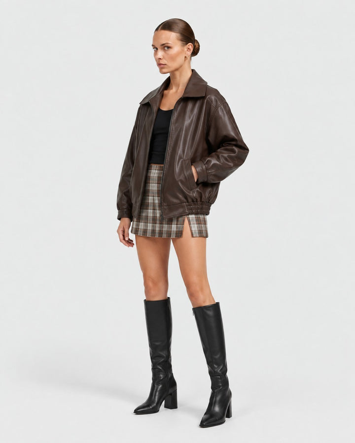 Luna Moda brown oversized PU leather jacket worn by a model with a plaid mini skirt and black knee-high boots