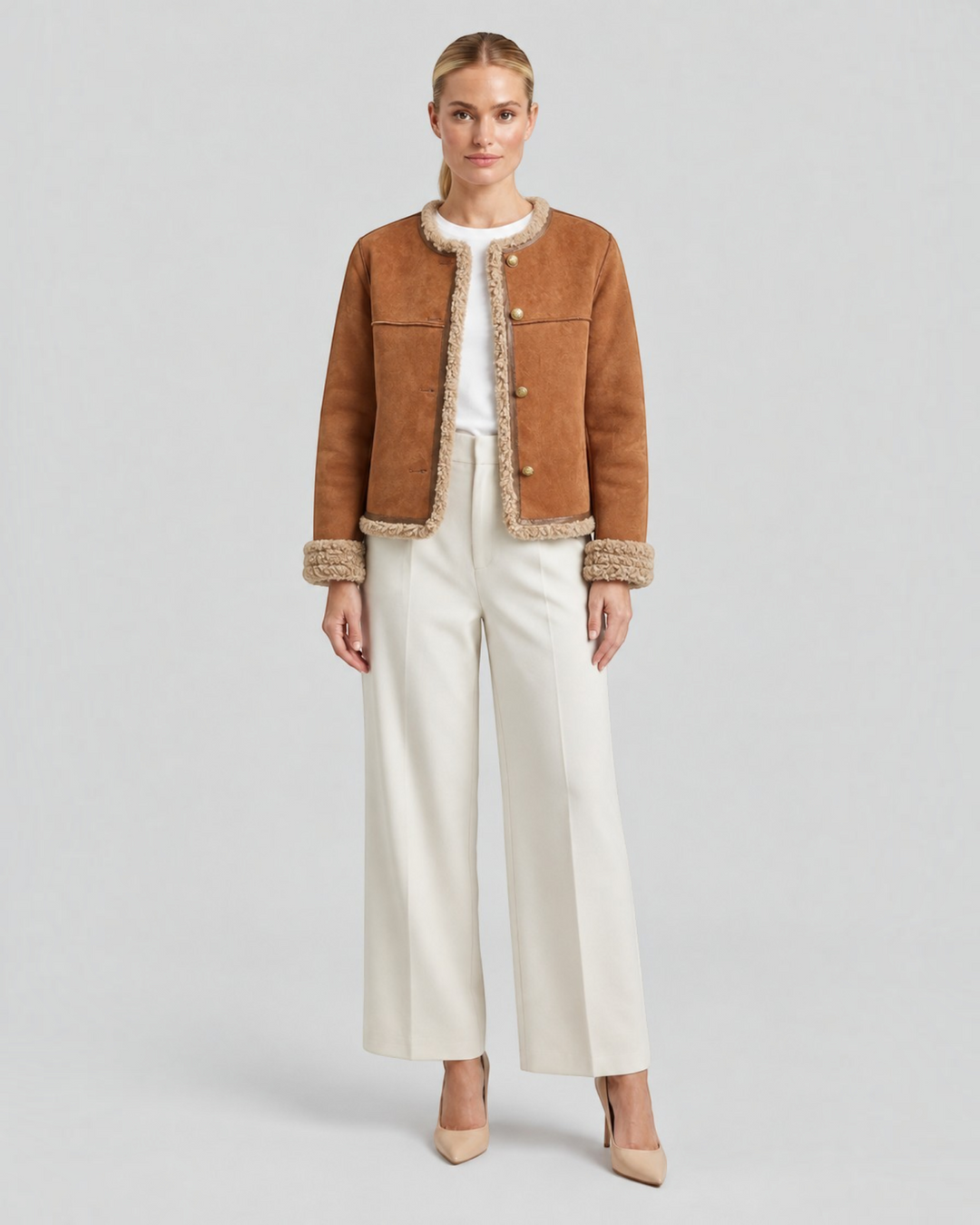 Luna Moda brown suede winter jacket with faux fur trim and gold buttons worn by a model with white trousers