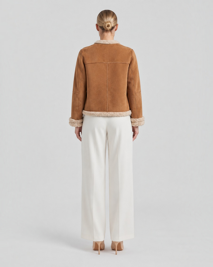 Luna Moda brown suede winter jacket with cream faux fur lining, back view on a model wearing white trousers.