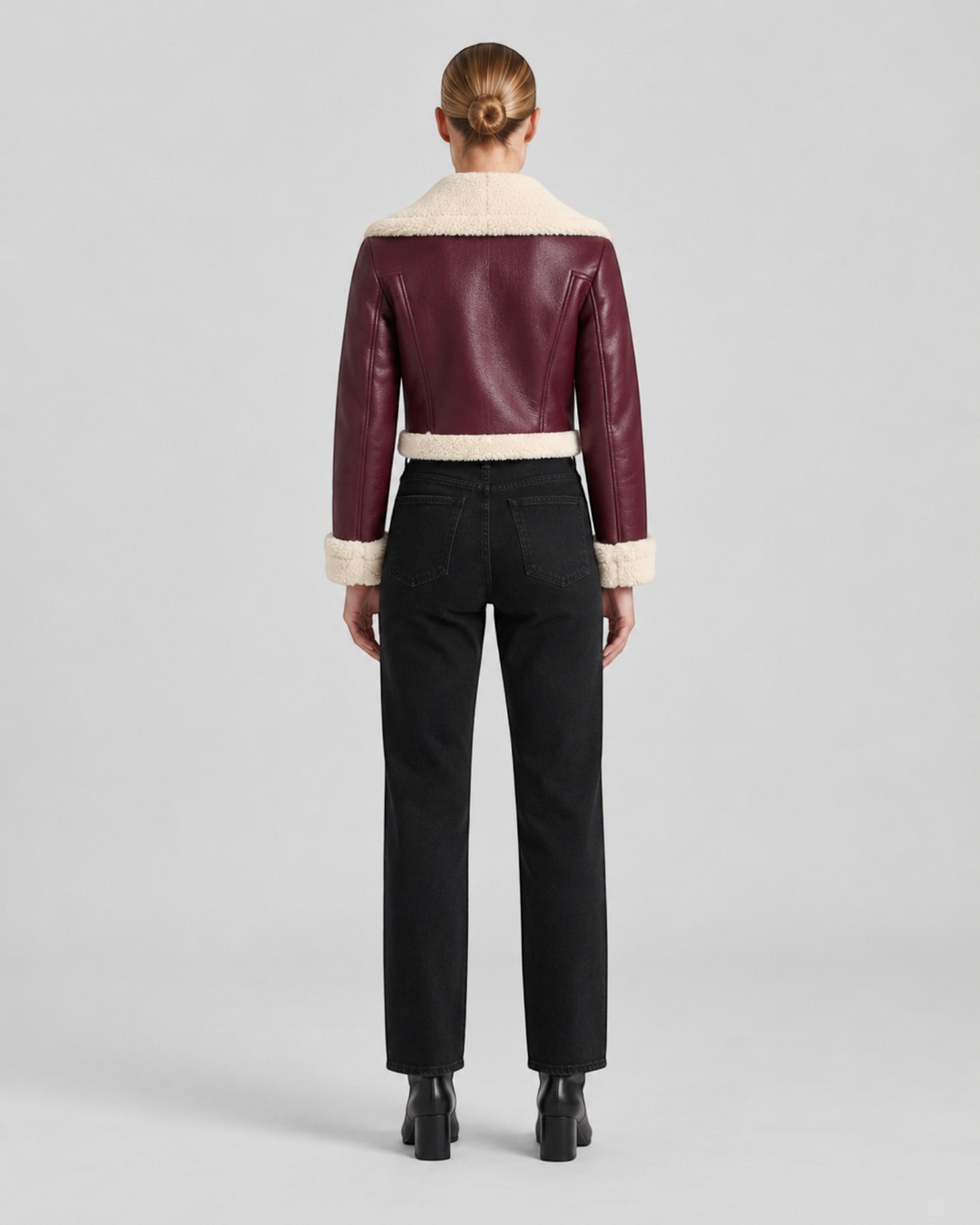 Luna Moda cropped burgundy faux leather jacket with cream fleece lining, back view on a model wearing black jeans.