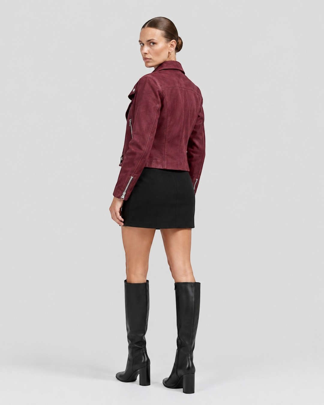 Luna Moda burgundy suede biker jacket with silver zippers worn by a model with a black skirt and knee-high boots