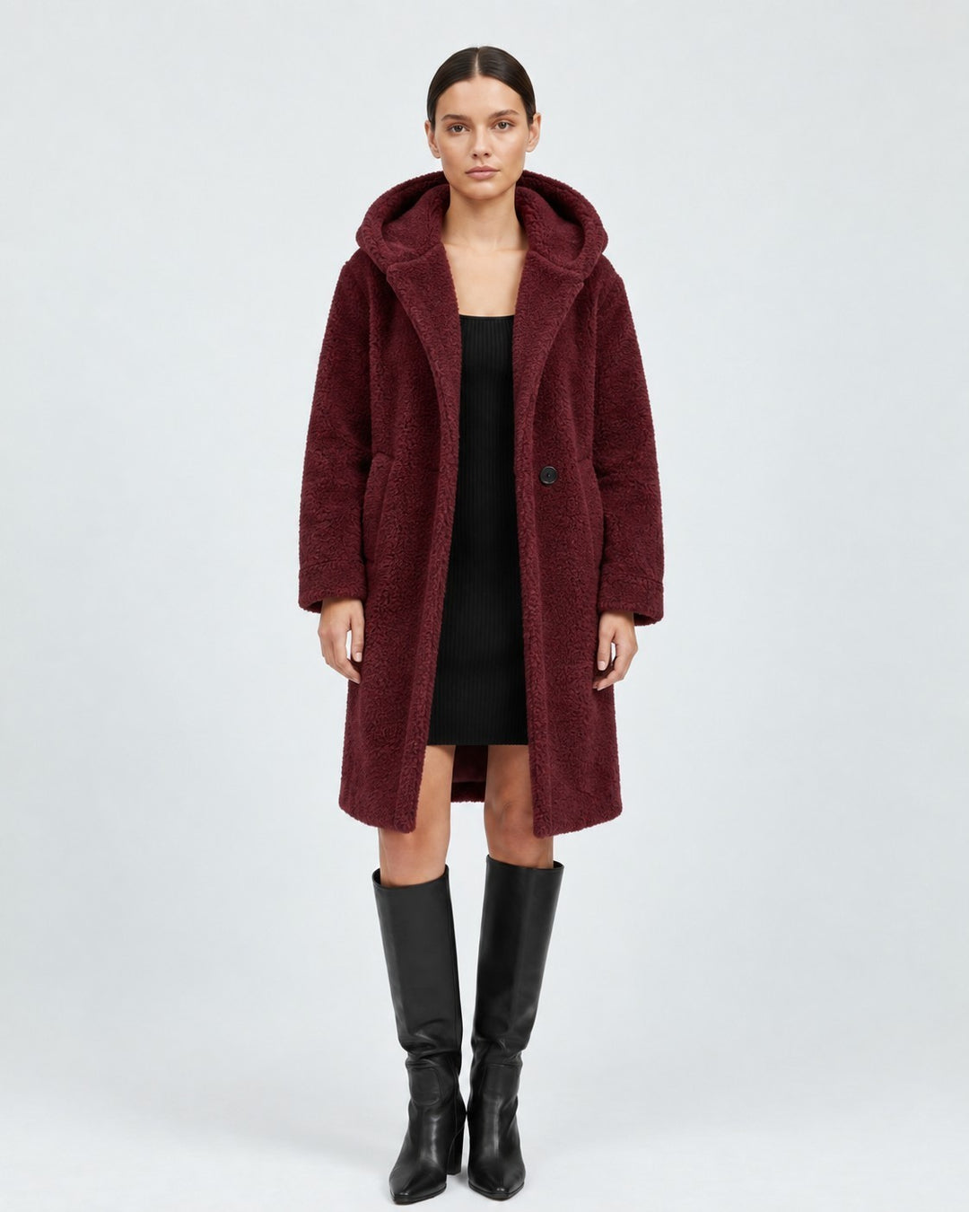 Luna Moda burgundy wool teddy coat with a hood and patch pockets, worn by a model over a black dress and boots.
