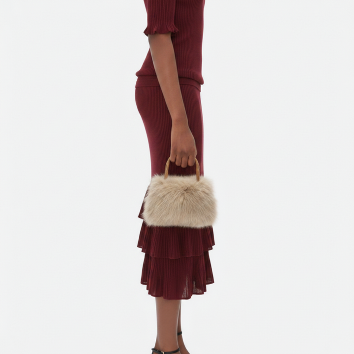 Luna Moda Carlotta small beige faux fur handbag with a wooden handle held by a model in a burgundy ribbed dress