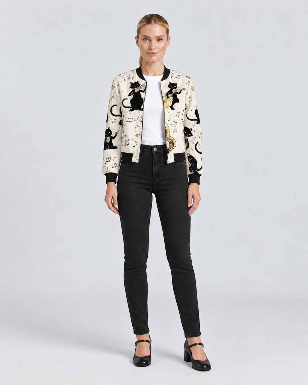 Luna Moda bomber jacket in cream with black cat and musical note print, worn with black jeans and heels.