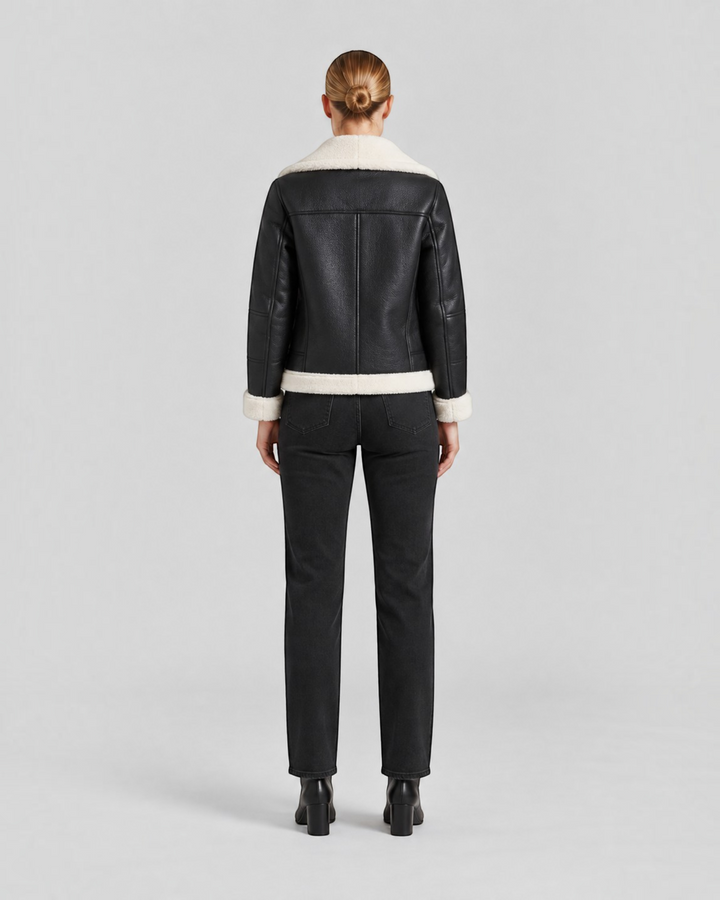 Back view of Luna Moda Claudia black faux leather jacket with white fleece lining and collar, worn with black jeans.