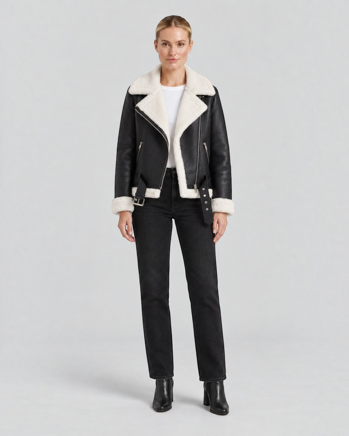 Luna Moda Claudia black faux leather jacket with white fleece lining, zip details, and waist belt on a model