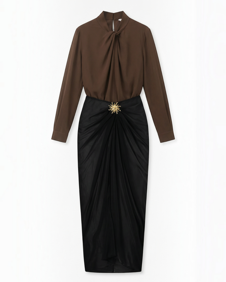 Luna Moda midi skirt in black with draped fabric and a gold sun-shaped brooch, paired with a brown long-sleeve top.