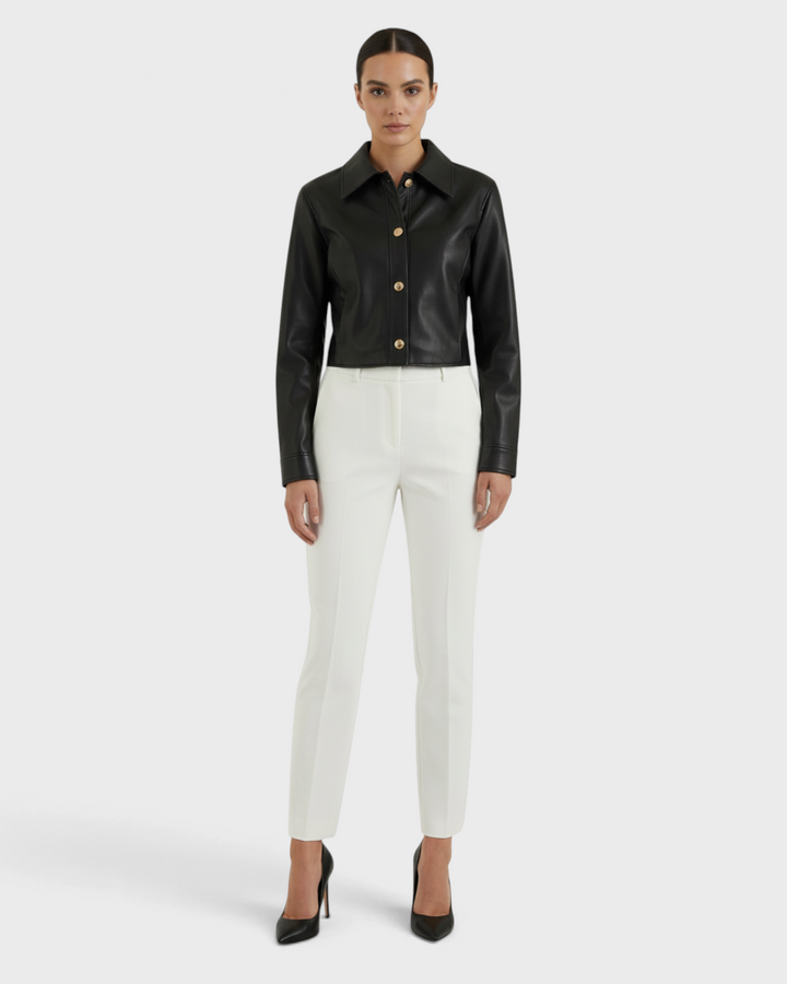 Luna Moda Elettra black faux leather cropped jacket with snap buttons worn by a model with white trousers