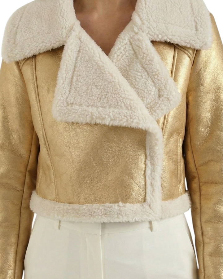 Luna Moda cropped gold metallic jacket with white faux shearling lining and wide lapels worn over white trousers.