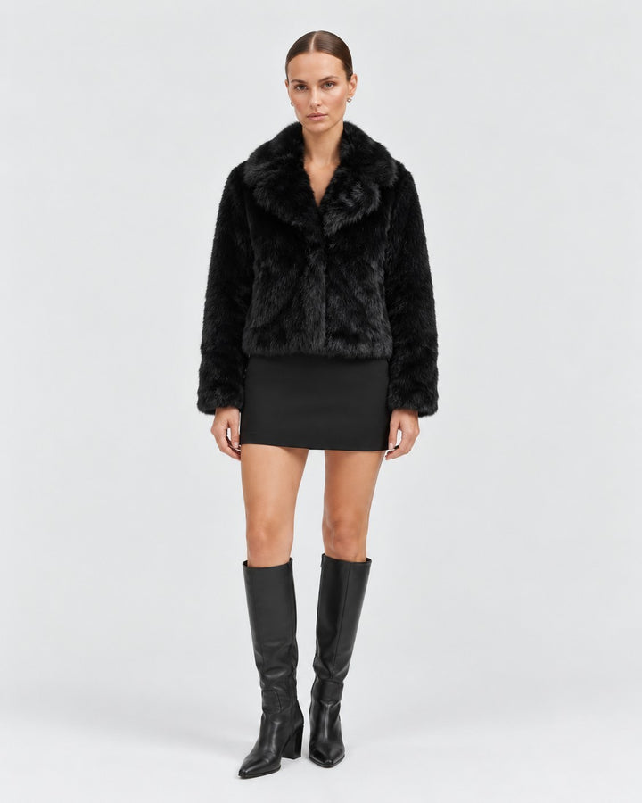 Luna Moda Debora black faux fur cropped jacket worn by a model with a black mini skirt and knee-high boots.