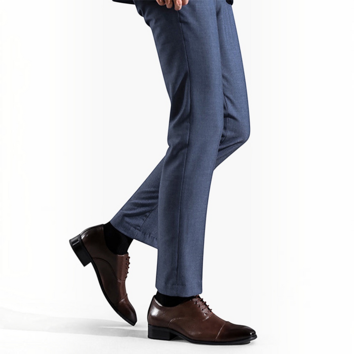 Luna Moda ETTORE dark brown leather dress shoes with fine stitching worn with blue trousers on a white background