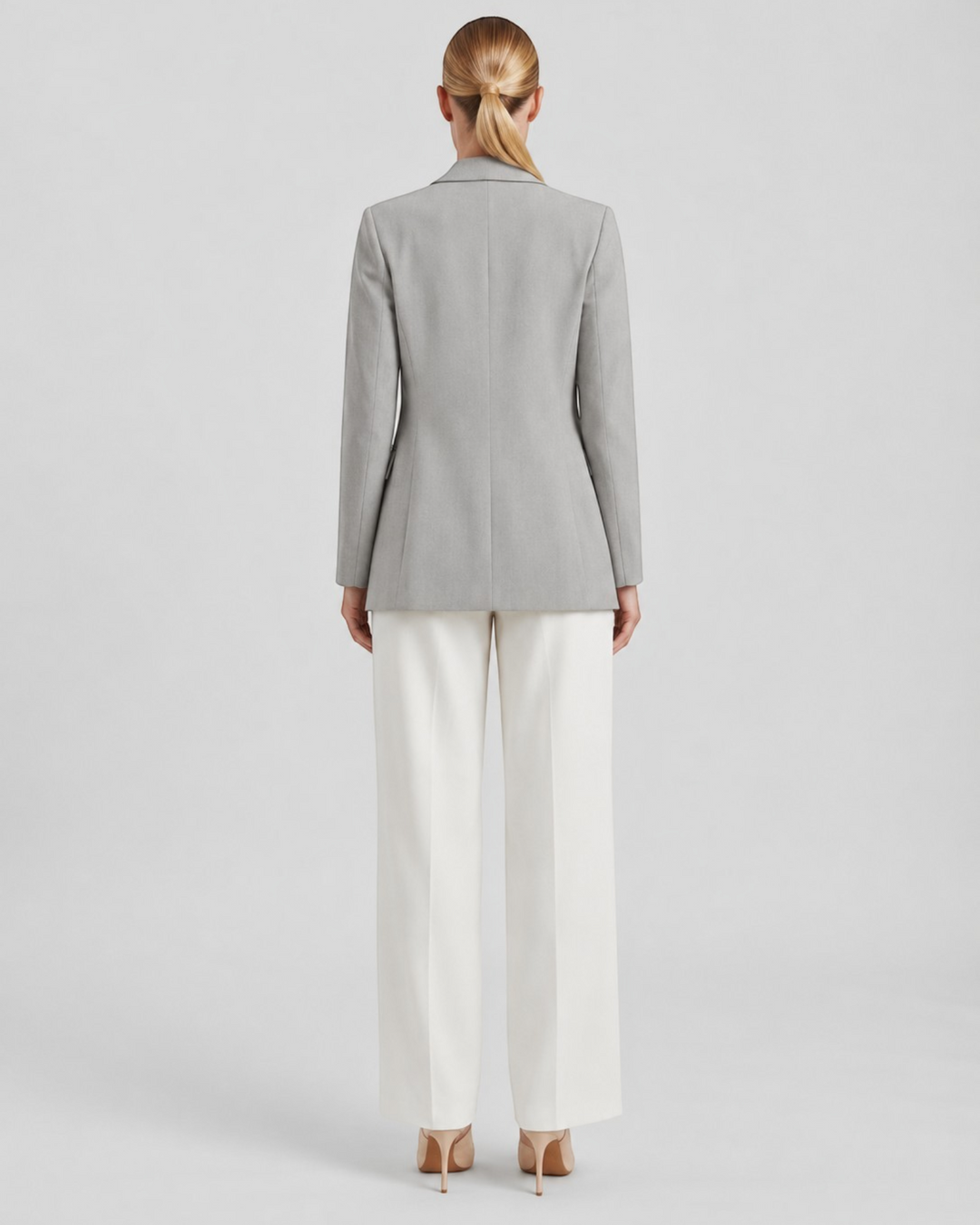 Luna Moda Felicia long grey blazer with a tailored waist and padded shoulders, worn with white trousers, back view.