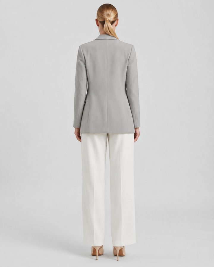 Luna Moda Felicia long grey blazer with a tailored waist and padded shoulders, worn with white trousers, back view.