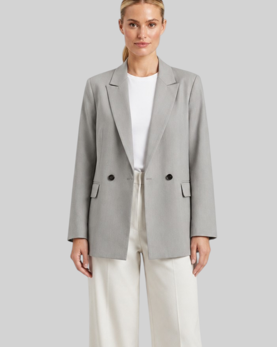 Luna Moda Felicia long grey blazer with padded shoulders and tailored waist worn by a woman with white trousers