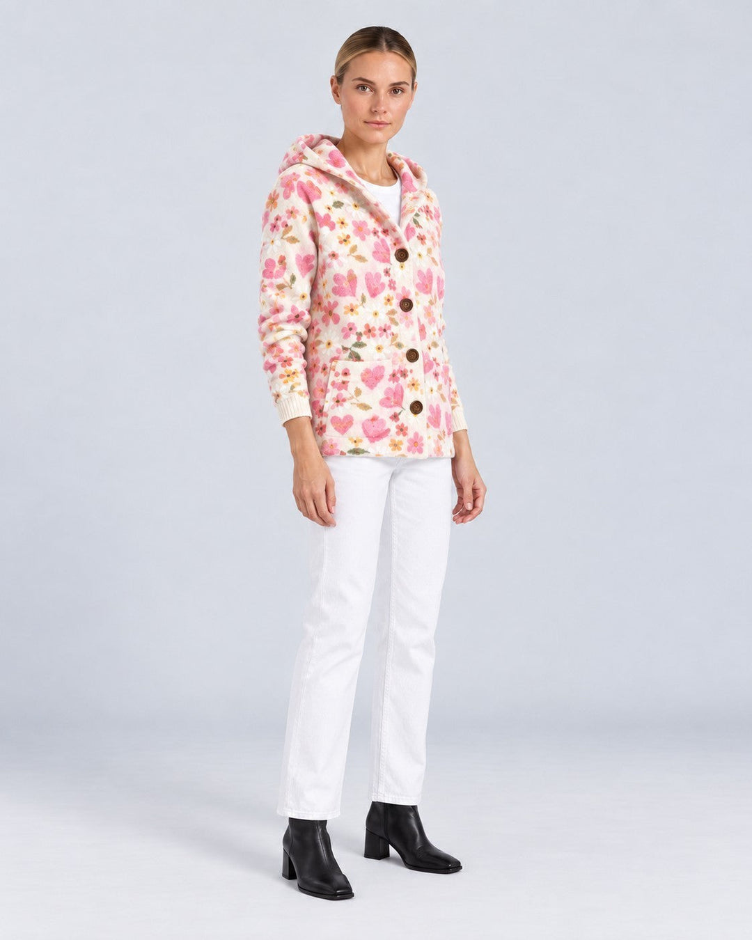 Luna Moda Gaia cardigan with hood, featuring a pink heart and floral print, worn by a model with white trousers.