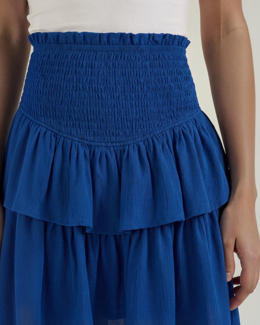 Luna Moda Grace blue mini skirt featuring a high-waisted smocked waistband and layered ruffled hem details.