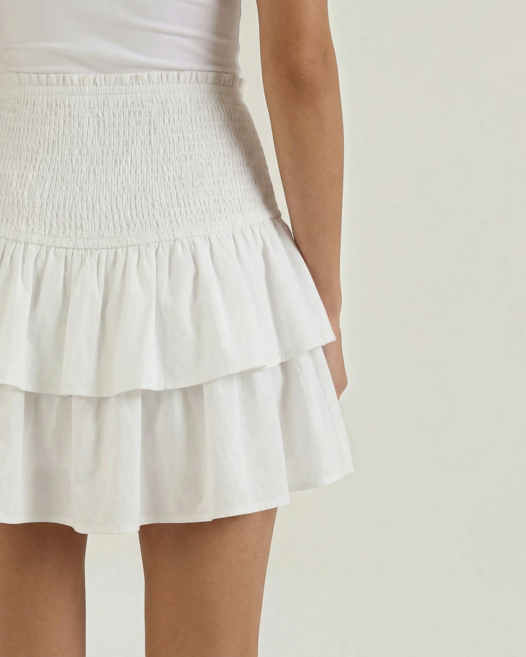 Luna Moda white mini skirt with a high-waisted smocked waistband and layered ruffled hem for a feminine look.