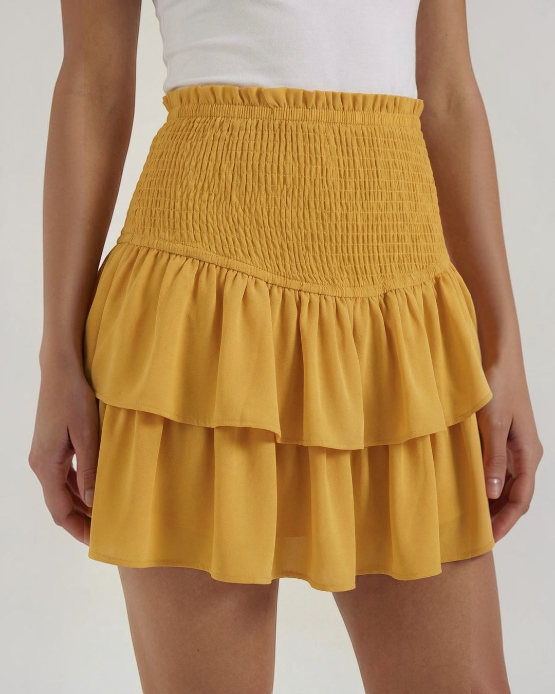 Luna Moda Grace mustard yellow mini skirt with a high-waisted smocked bodice and layered ruffled hem.