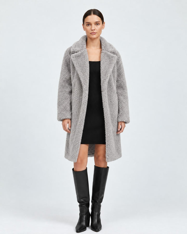 Luna Moda grey faux fur teddy coat with lapels worn by a model over a black dress and knee-high boots