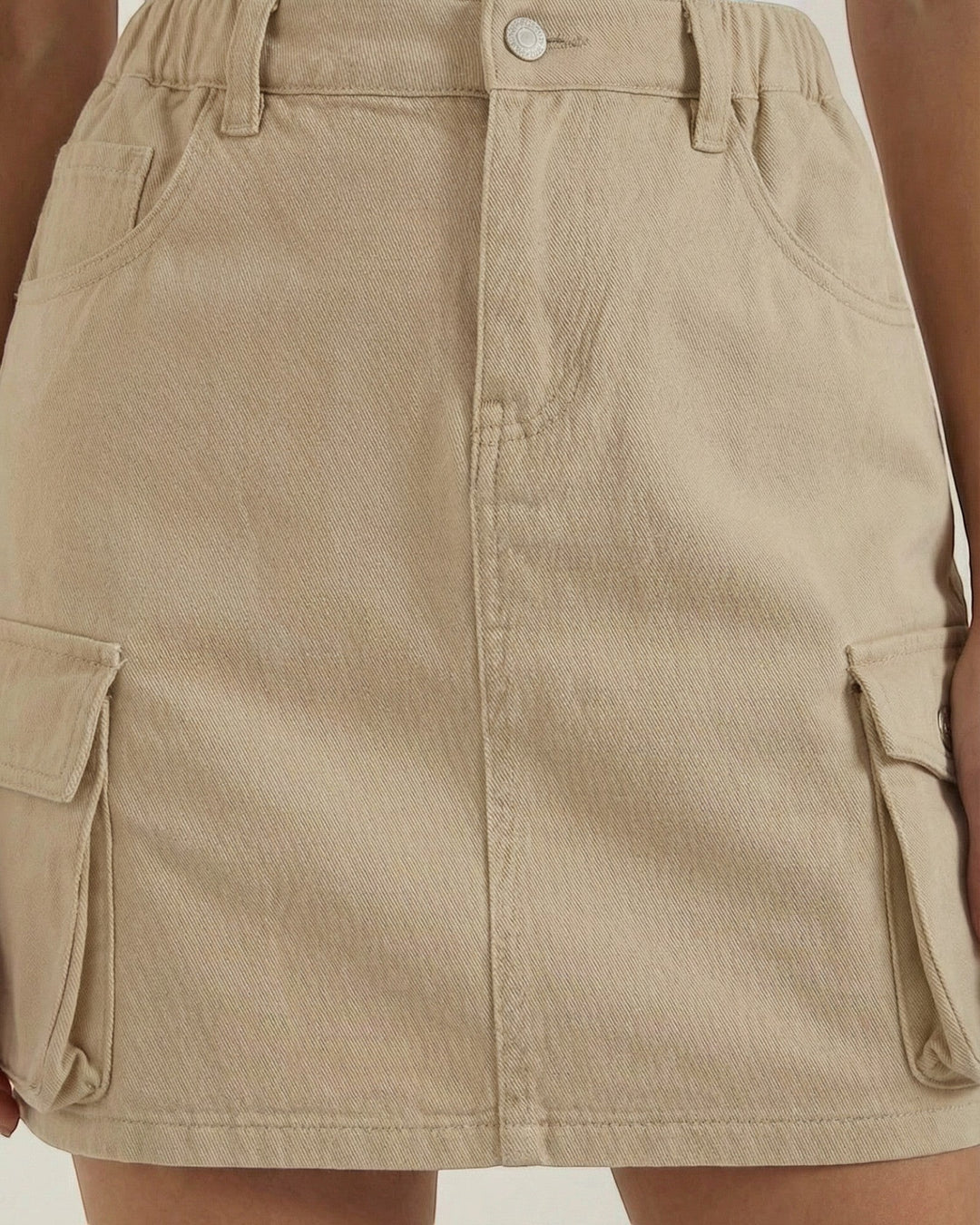 Luna Moda beige A-line cargo mini skirt with an elastic waistband and functional side pockets worn with a white top