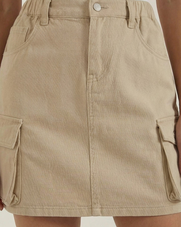 Luna Moda beige A-line cargo mini skirt with an elastic waistband and functional side pockets worn with a white top