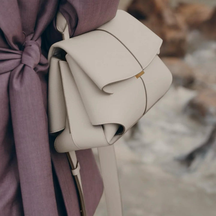 Luna Moda Lara minimal beige leather handbag with a structured flap design and adjustable strap worn over the shoulder