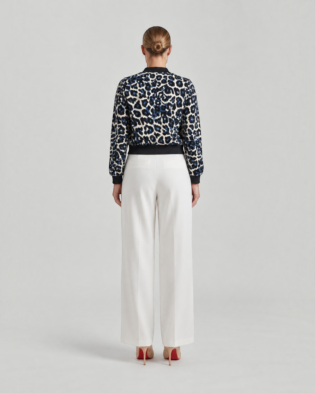 Luna Moda leopard print bomber jacket with ribbed cuffs worn by a woman with white trousers, back view