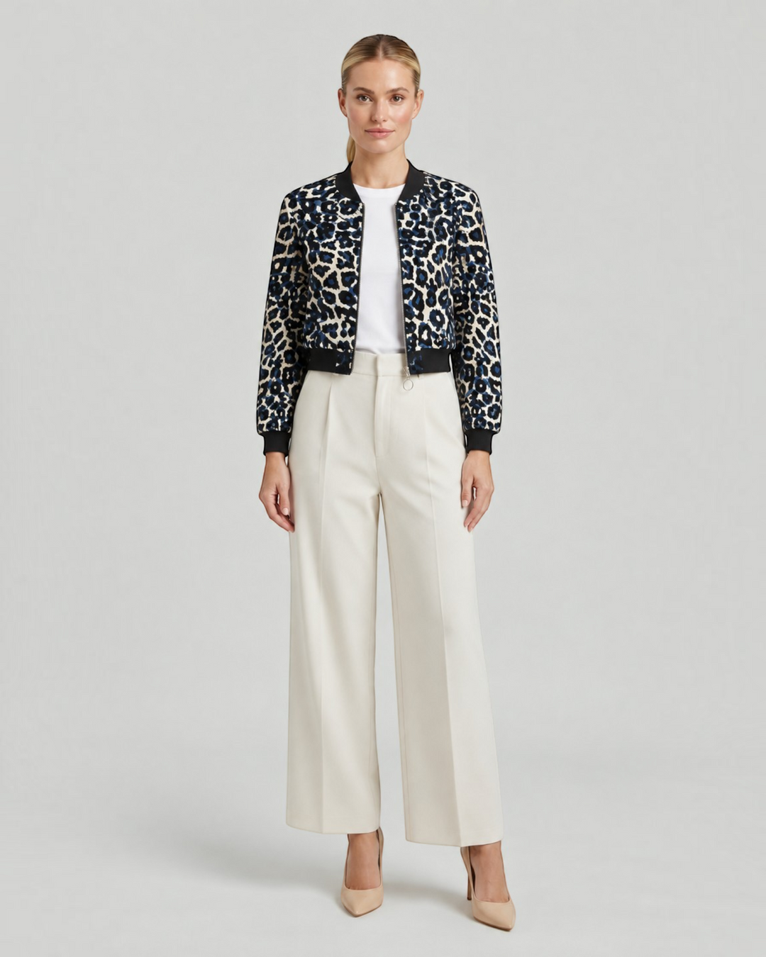 Luna Moda leopard print bomber jacket with black ribbed cuffs and collar worn by a model with cream trousers