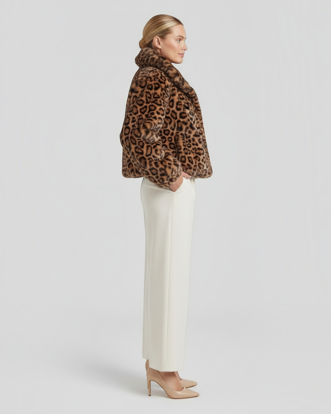 Luna Moda leopard print faux fur coat worn by a model with cream trousers and beige heels, side profile view.