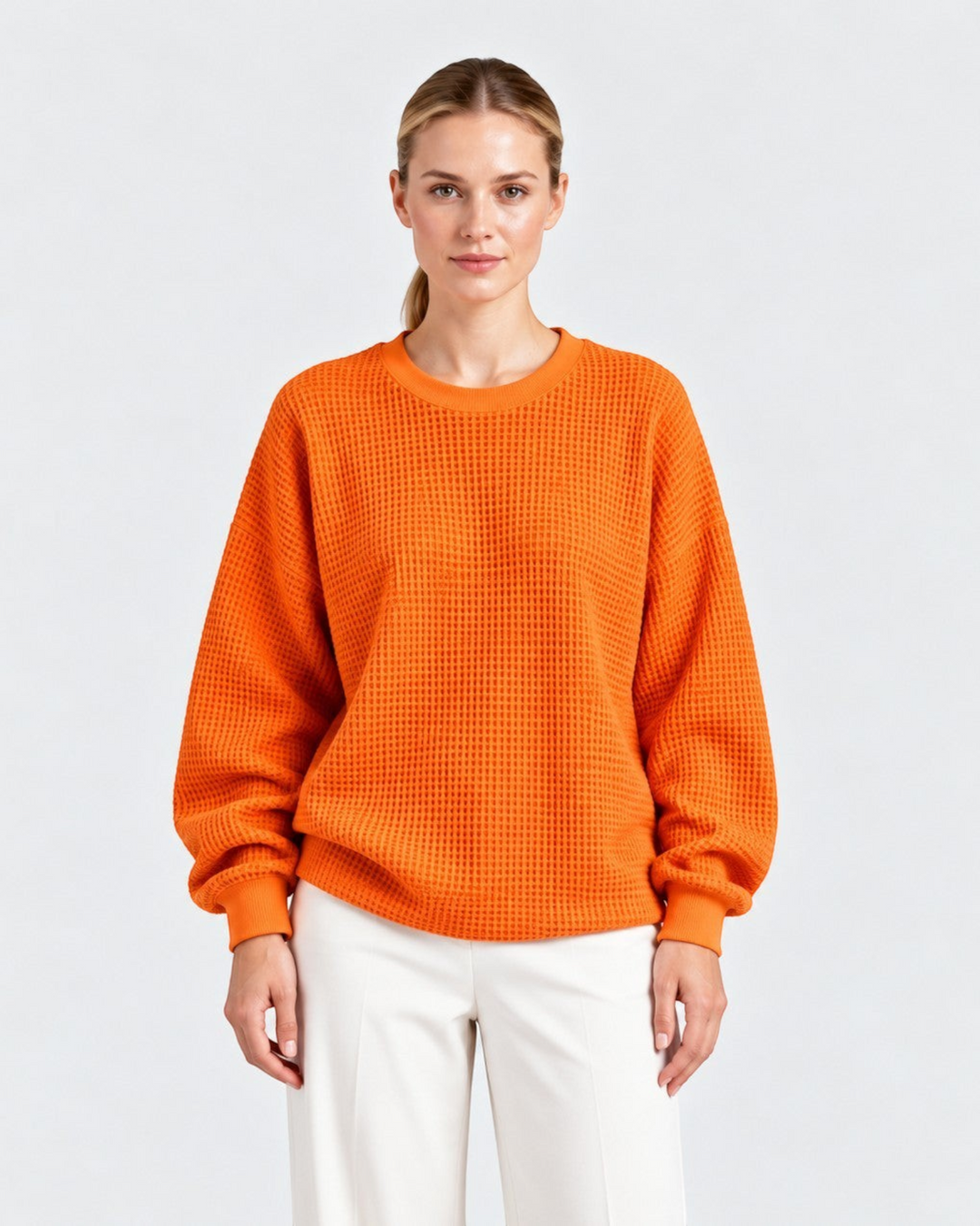 Luna Moda Lucia oversized orange waffle knit sweater with crew neck worn by a woman with white trousers