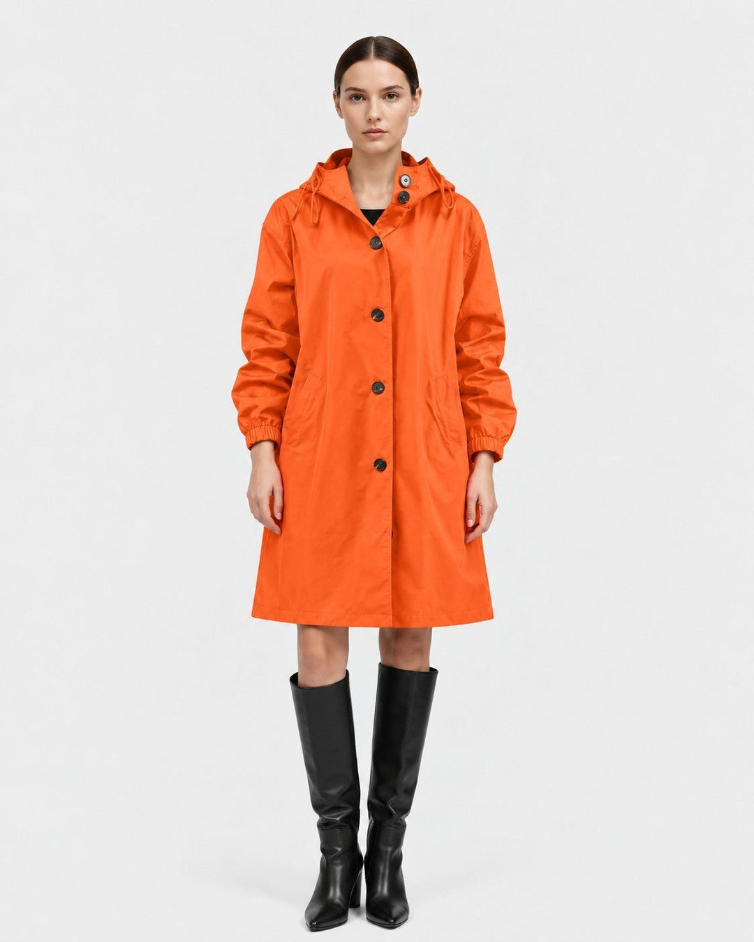 Luna Moda Lucie orange oversized waterproof raincoat with hood and pockets worn by a model with black boots