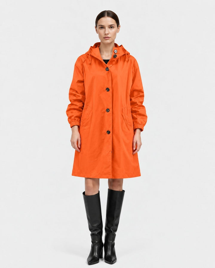 Luna Moda Lucie orange oversized waterproof raincoat with hood and pockets worn by a model with black boots