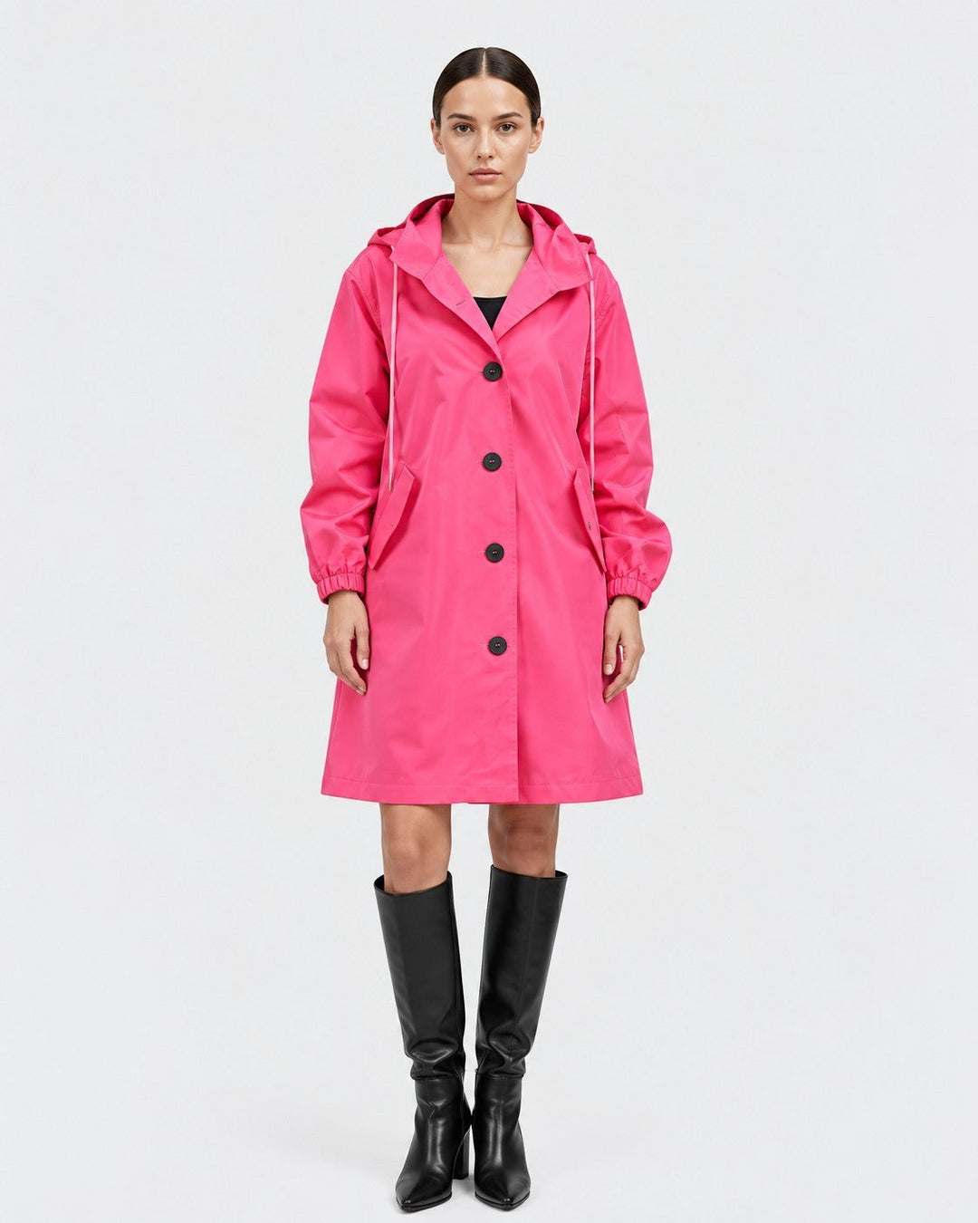 Luna Moda Lucie oversized hot pink waterproof hooded raincoat with button closure and pockets worn by a model