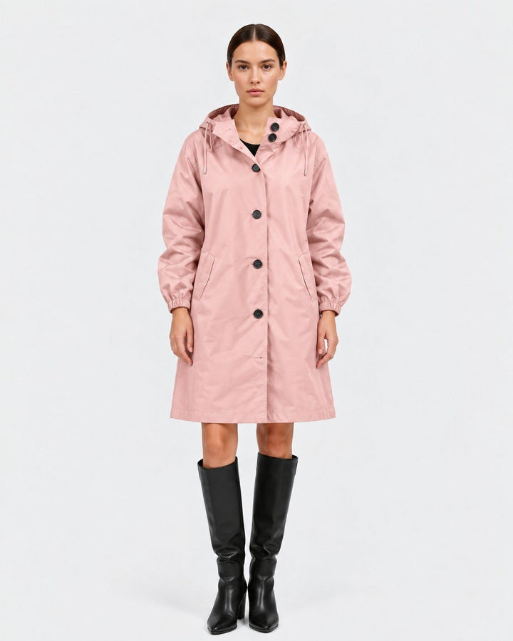 Luna Moda Lucie oversized waterproof pink raincoat with hood and pockets worn by a model with black boots