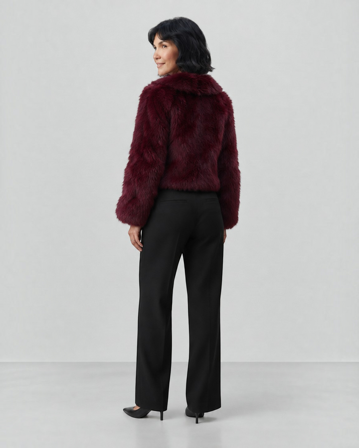 Luna Moda Margherita burgundy faux fur coat with wide collar worn by a woman with black trousers, back view