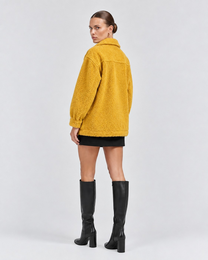 Model wearing a mustard yellow Luna Moda textured fleece jacket with a collar, paired with a black skirt and boots.
