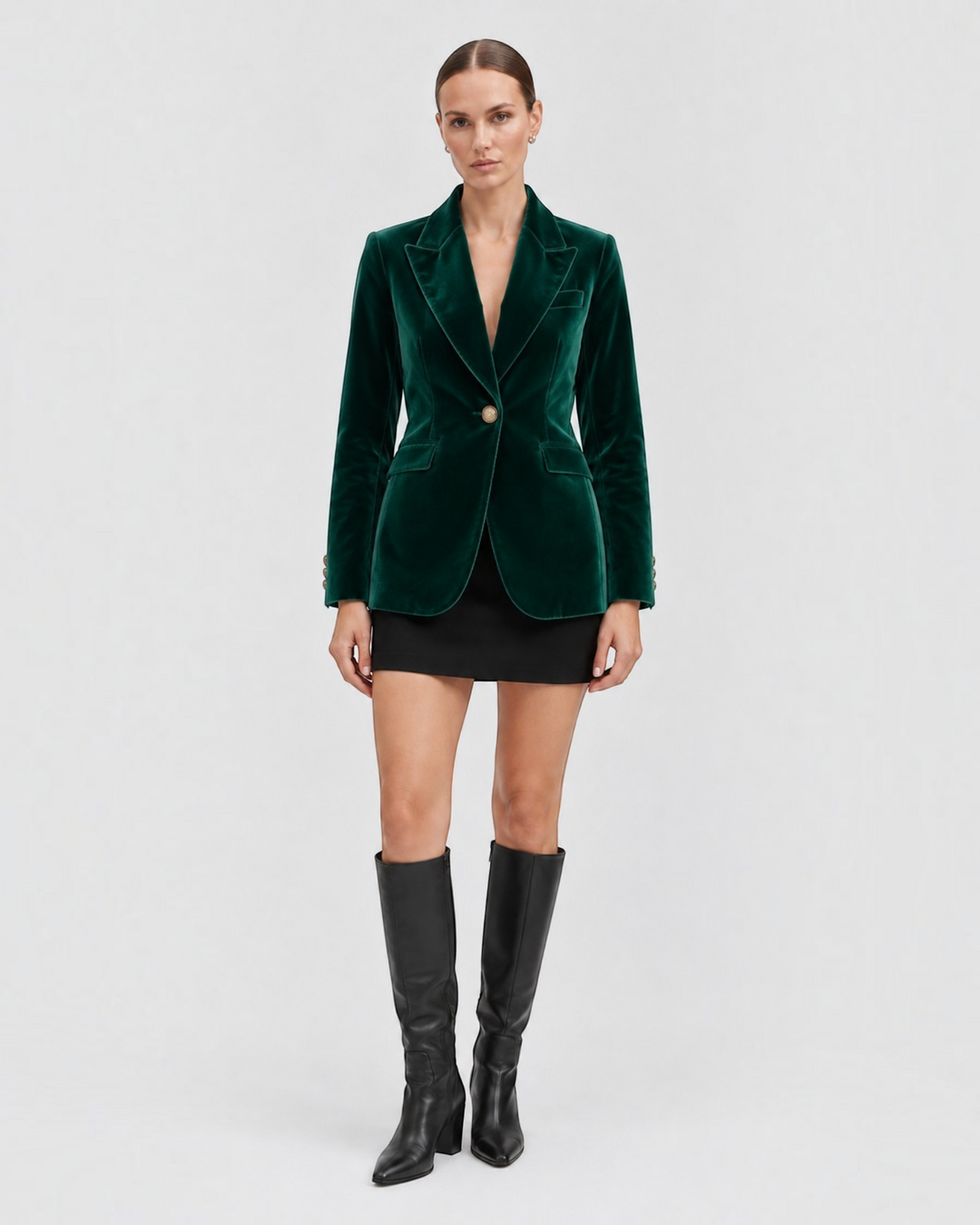 Luna Moda Natálie tailored emerald green velvet blazer worn by a model with a black mini skirt and knee-high boots