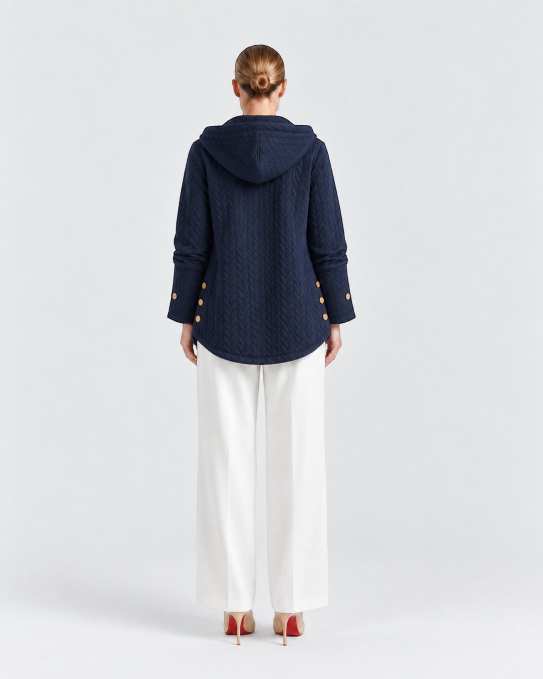 Luna Moda navy blue quilted hooded jacket with decorative side buttons worn by a woman with white trousers