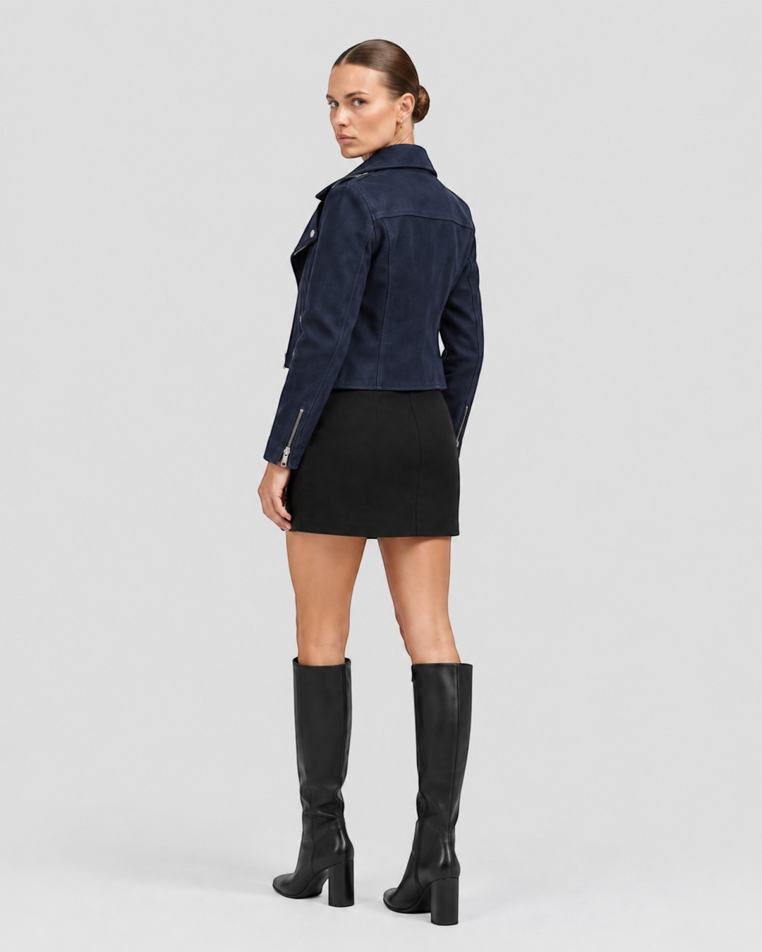 Luna Moda navy blue suede biker jacket with silver zippers worn by a model with a black skirt and knee-high boots