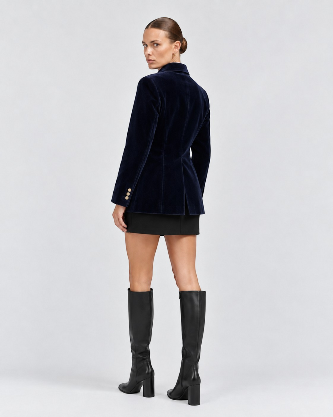 Luna Moda navy blue velvet tailored blazer worn by a model with black skirt and knee-high boots, back view